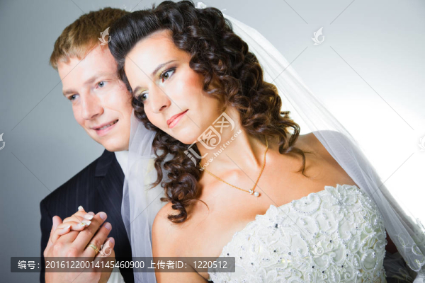 年輕優(yōu)雅的迷戀剛結(jié)婚的新娘和新郎抱著灰色背景的工作室肖像
