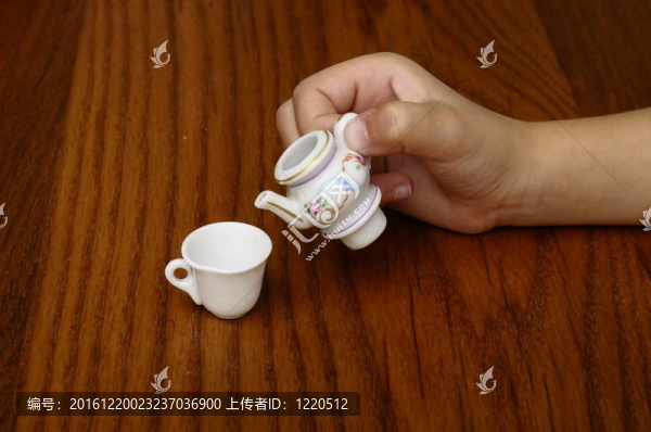 小孩用手在茶杯里倒茶