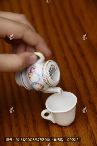 小孩用手在茶杯里倒茶