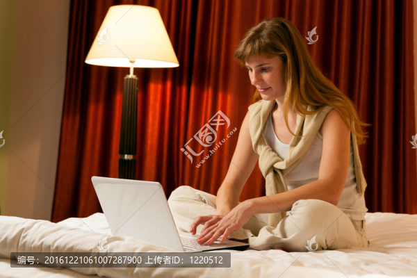 在酒店使用筆記本電腦的年輕女性