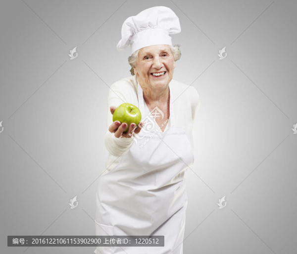 高級女廚師提供一個綠色蘋果對灰色背景