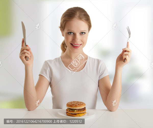 吃晚飯的時(shí)候。帶刀叉的年輕女子；和漢堡包