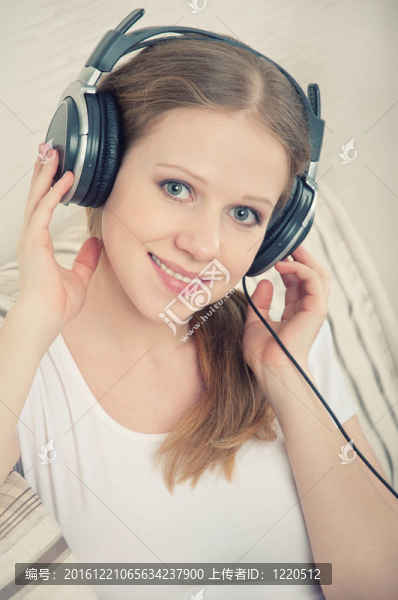 美麗的年輕女子躺在沙發(fā)上欣賞耳機上的音樂