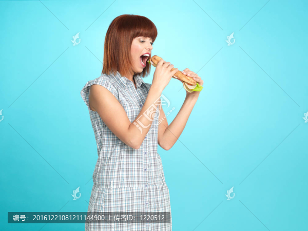 漂亮的年輕女人在吃一個大三明治