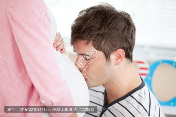 一個細心的男人吻著他懷孕妻子的肚子