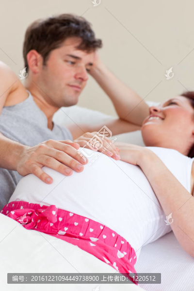快樂的白人孕婦與丈夫躺在床上
