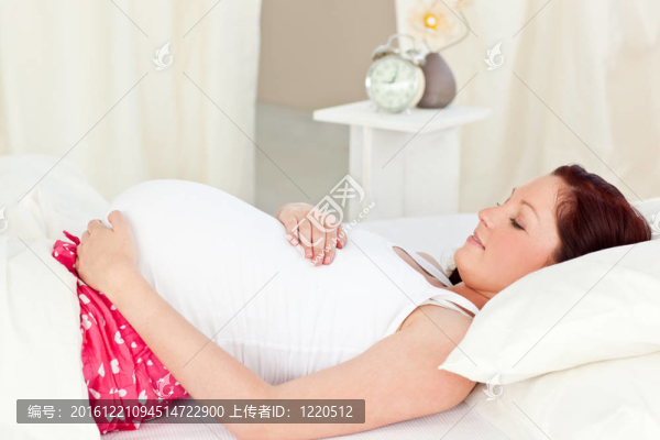一個幸福的孕婦躺在床上，在家里摸她的肚子