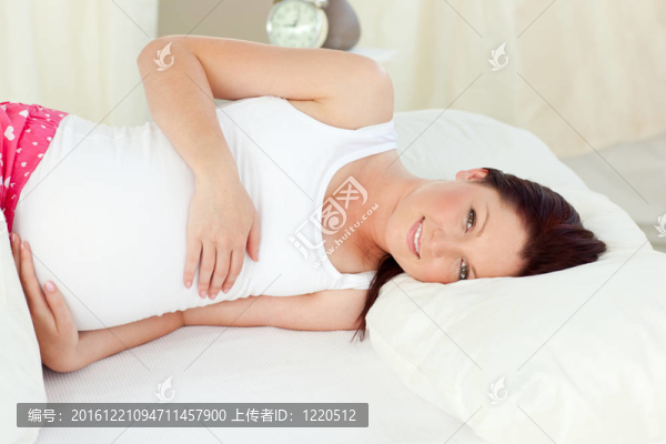 明亮的孕婦在臥室撫摸她的肚子