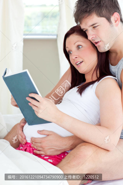 一個震驚的孕婦和她的丈夫在家里的沙發(fā)上看書