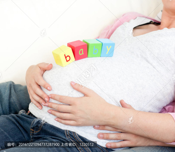 一個懷孕的婦女在她的腹部和她的丈夫躺在沙發(fā)上在家里的嬰兒
