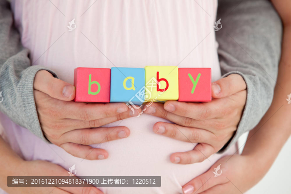 一個孕婦的腹部和她丈夫抱著嬰兒立方體的特寫