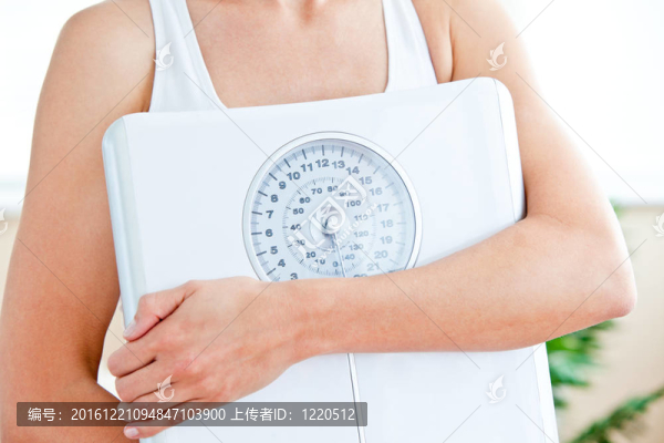 一個(gè)西班牙婦女在客廳里拿著一個(gè)秤