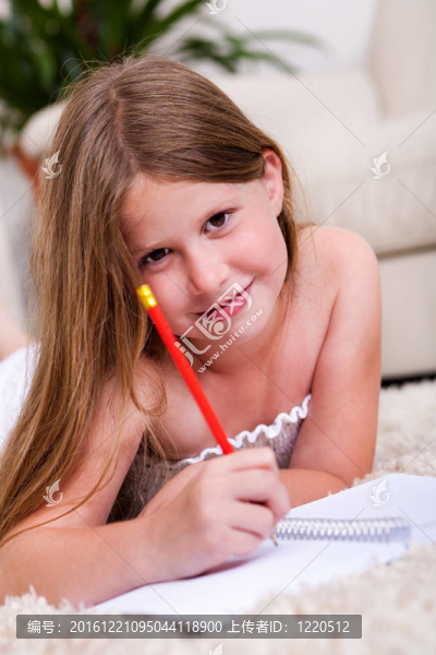微笑的少女躺在筆記本上寫(xiě)字