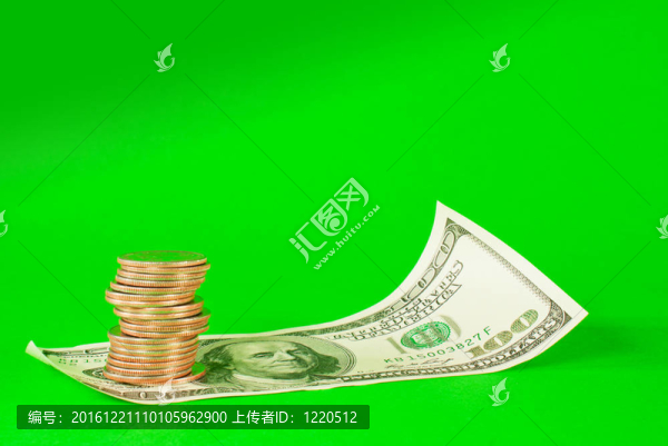 堆放在100美元紙幣堆疊的酒吧里的硬幣