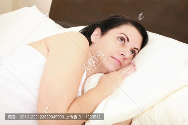 一個年輕女子躺在床上醒著。不眠沉思。