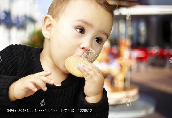 漂亮的小孩吃餅干對旋轉(zhuǎn)木馬的肖像