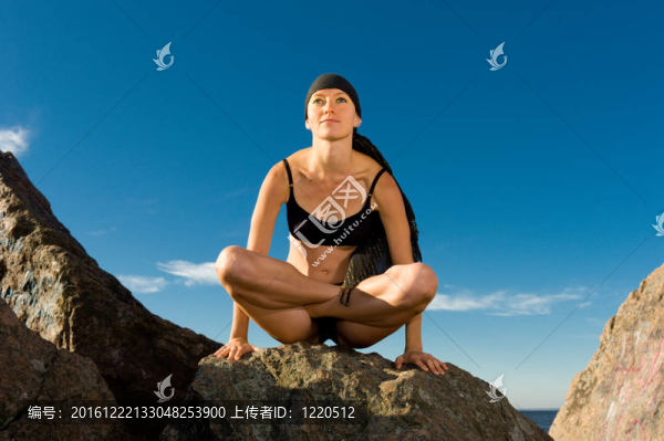 美麗的女子坐在蓮花姿勢在海灘上