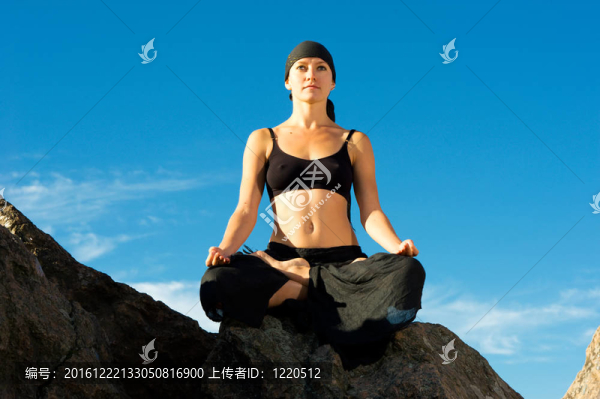 美麗的女子坐在蓮花姿勢(shì)在海灘上