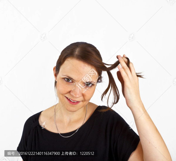 迷人的年輕女子微笑著玩弄她的頭發(fā)