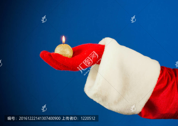 Santa手在藍(lán)色背景上手持燃燒的蠟燭