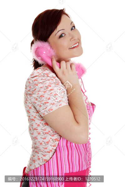 快樂的女人在粉紅色的廚房圍裙上打電話。