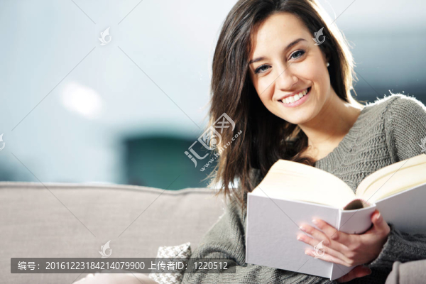 一個幸福的年輕女子躺在沙發(fā)上的書