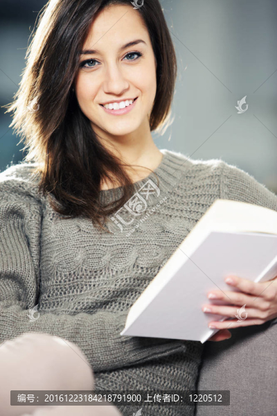 一個幸福的年輕女子躺在沙發(fā)上的書
