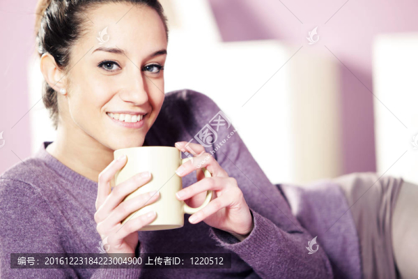 一個(gè)漂亮的年輕女子在床上捧著一杯咖啡的畫像