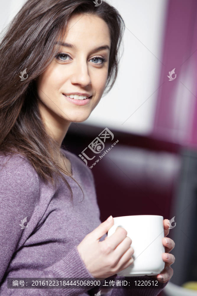 美麗的年輕女子在廚房喝咖啡