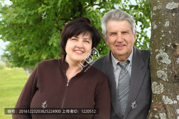 老人和他的成年女兒站在樹旁微笑