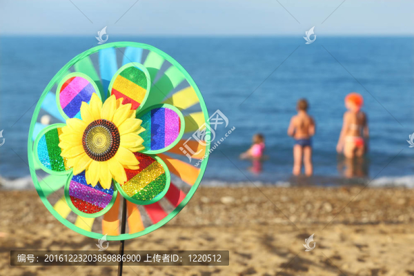 五彩風(fēng)車玩具花在海灘上；家庭常備