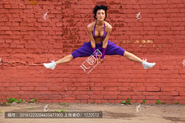 穿著紫色衣服的苗條女孩跳上磚墻的背景