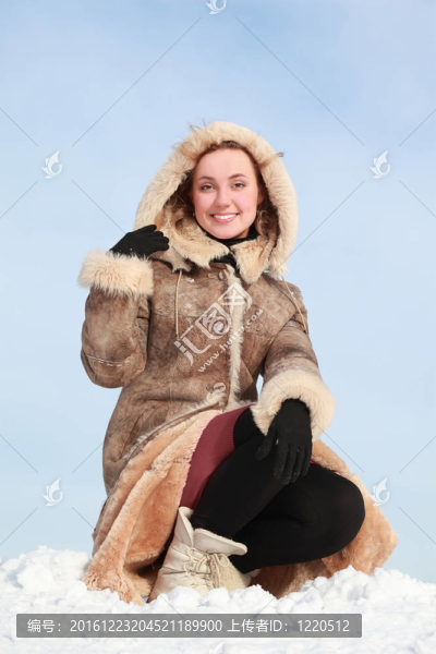 年輕女子蹲在雪地上，手持兜帽