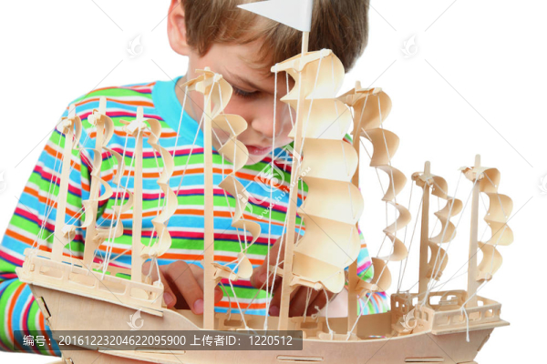 穿條紋襯衫的小男孩對人造船體充滿熱情