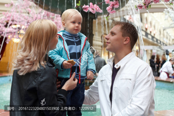 三口之家步行。父母看著孩子。