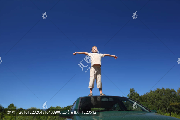男孩站在汽車的頭上，抬起天空的臉，雙手放在一邊