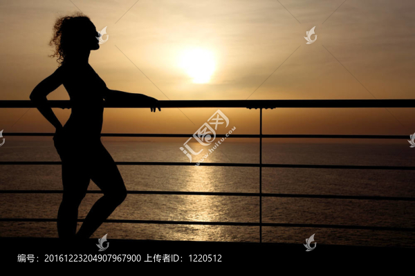 站在郵輪甲板上的卷發(fā)女孩剪影；手欄桿；側(cè)視圖；背景日落