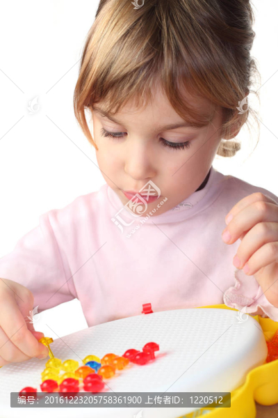 穿著粉色襯衫的小女孩玩彩色塑料馬賽克，看著它