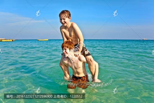 兄弟們正享受著清澈溫暖的水在美麗的海灘和玩子