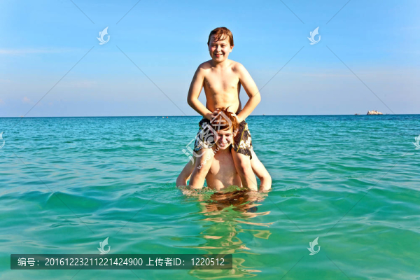 兄弟們正享受著清澈溫暖的水在美麗的海灘和玩子