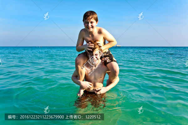 兄弟們正享受著清澈溫暖的水在美麗的海灘和玩子