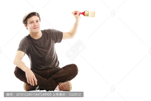 年輕的微笑男子持有油漆刷