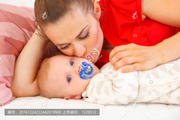 年輕的母親躺在沙發(fā)上親吻嬰兒