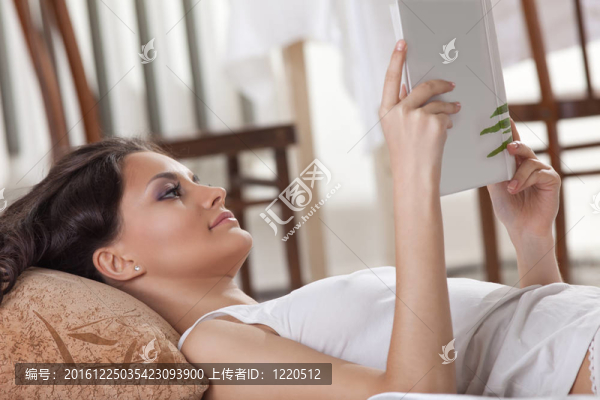 年輕女子躺在床上看書
