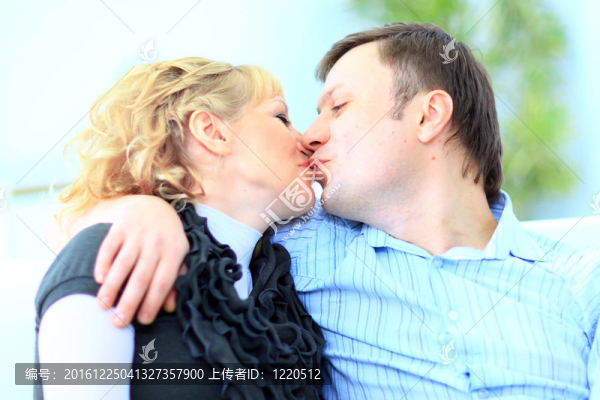 一個(gè)親熱的男人親吻妻子坐在家里的床上