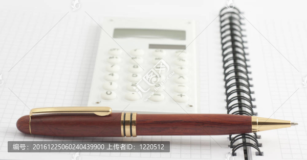 筆和白色計(jì)算器上的螺旋記事本