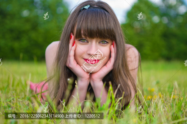 紅色的無袖短上衣的漂亮女孩躺在綠色的草地上