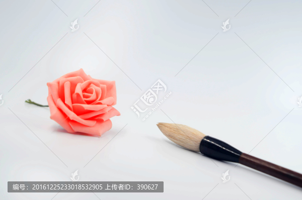 白色背景上的粉色玫瑰花和毛笔
