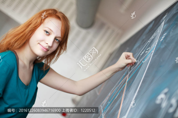 年輕漂亮的大學生在黑板上寫字