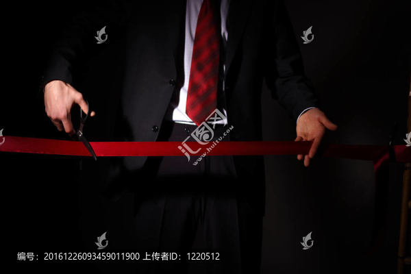 用剪刀切一個紅絲帶的商人
